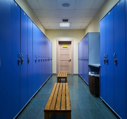 Luxury clean dressing room. Large blue lockers and wooden bench in a Lockers room in fitness gym