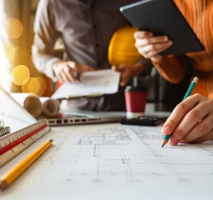 Two colleagues discussing data working and tablet, laptop with on on architectural project at construction site at desk in office